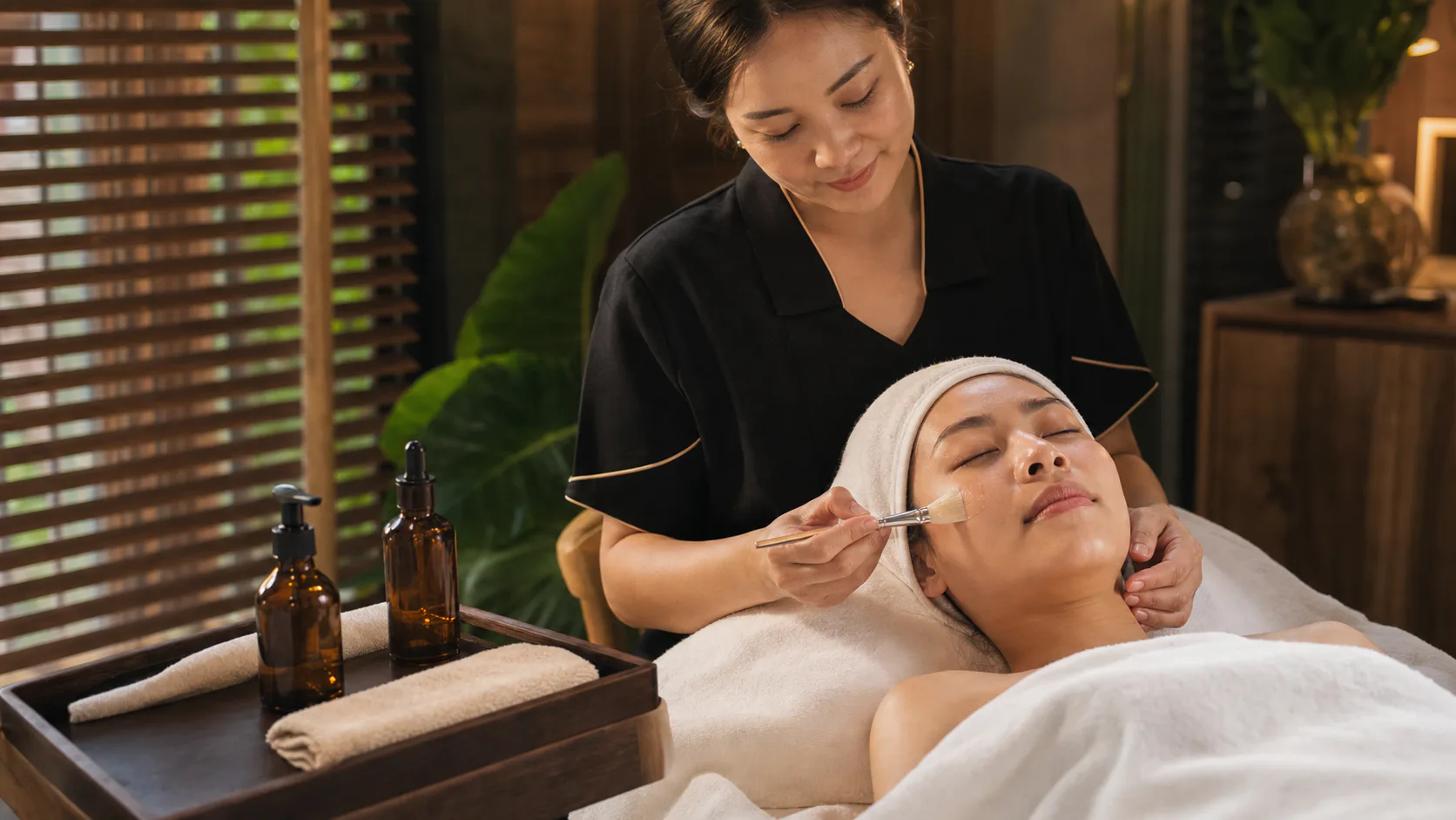 Thai therapist applying a hydrating facial serum during a skin recovery ritual in Bangkok
